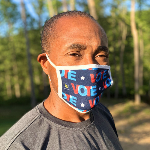 A person wears a mask that says VOTE and has HRC logos.